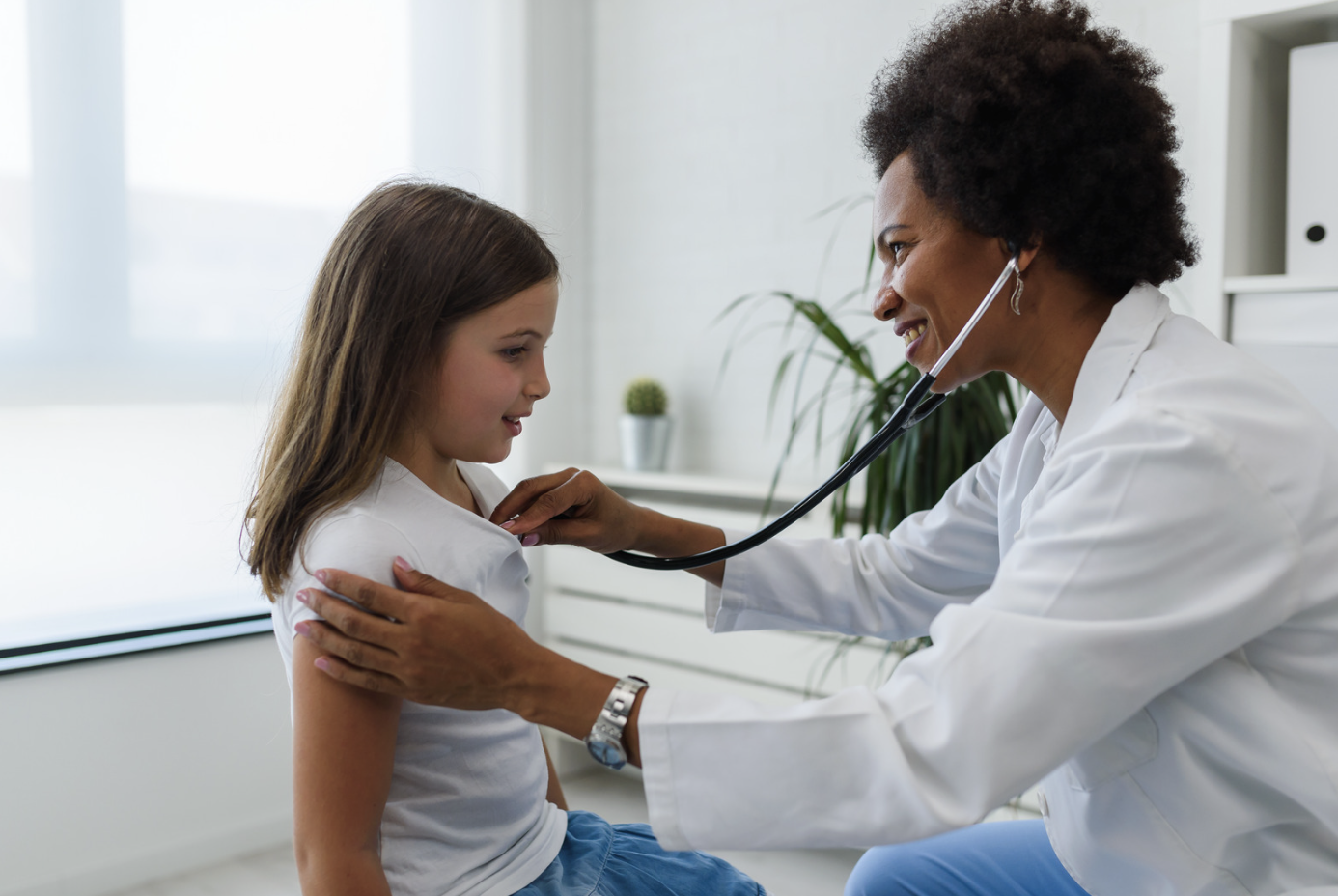 Pediatrician examining a smiling young girl
